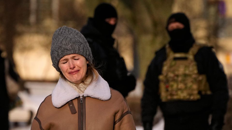 Polizisten beobachten eine weinende Frau, die dem verstorbenen Kremlgegner Alexej Nawalny gedenkt