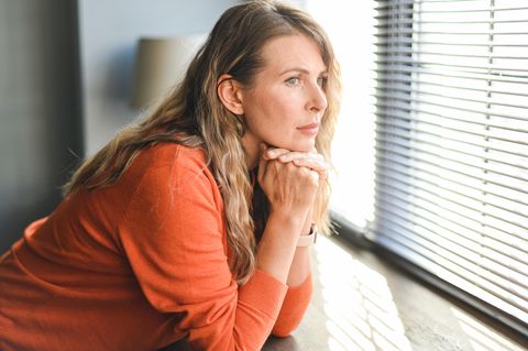 Eine erwachsene Frau schaut aus dem Fenster