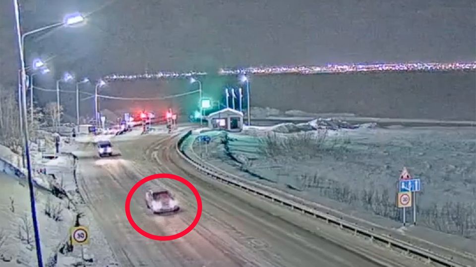 Ein Auto fährt eine verschneite Straße entlang.