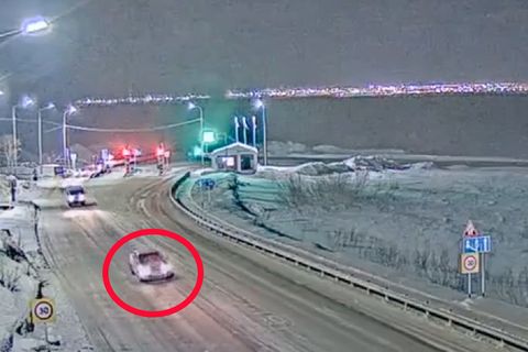 Ein Auto fährt eine verschneite Straße entlang.