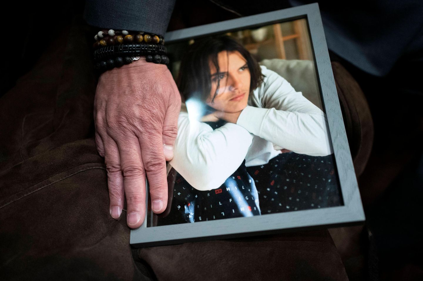 Ein Mann legt seine Hand auf das Foto seines Sohnes Daniel Puerta-Johnson, der an einer Fentanyl-Vergiftung gestorben ist