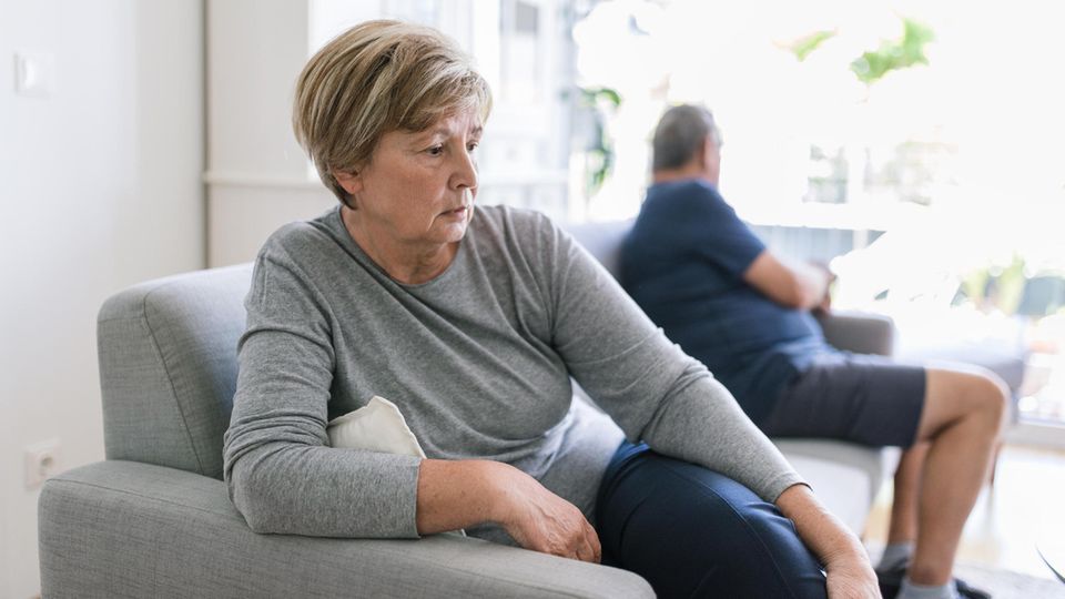 Scheidung: Ein getrenntes Ehepaar sitzt weit auseinander auf dem Sofa