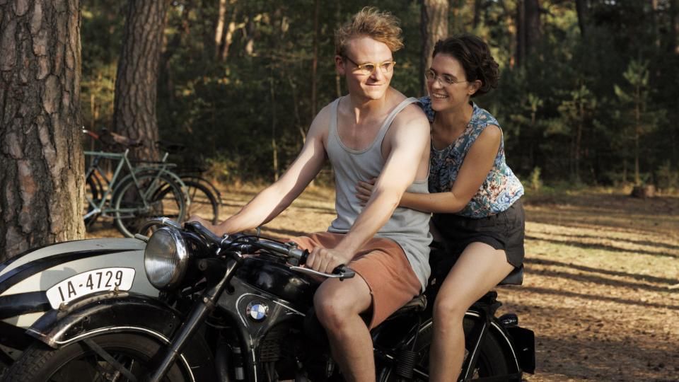Hans (Johannes Hegemann) und Hilde (Liv Lisa Fries) in Sommerklamotten auf einem alten Motorrad