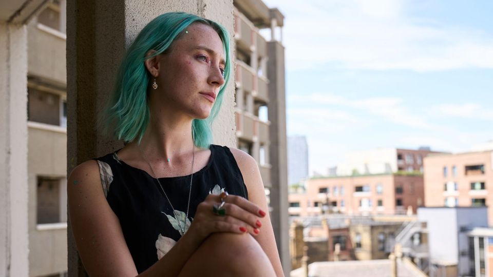 Schauspielerin Saoirse Ronan in "The Outrun" mit grünen Haaren am Fenster sitzend