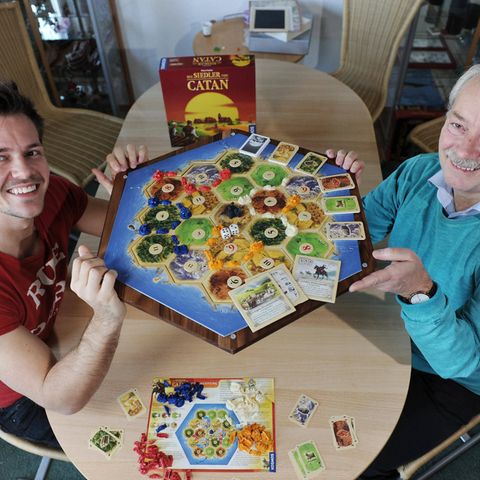 Zwei Männer mit Brettspiel. Es ist "Die Siedler von Catan"