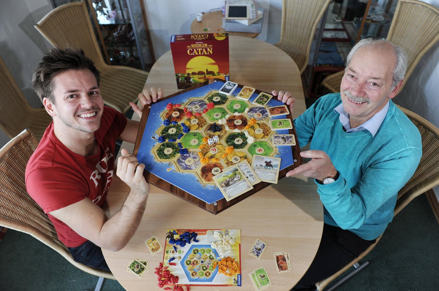 Zwei Männer mit Brettspiel. Es ist "Die Siedler von Catan"