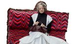 Schauspielerin Maggie Smith auf einem roten Sofa sitzend