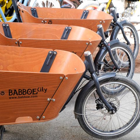 Drei hintereinander aufgereihte Lastenfahrräder der Marke Babboe
