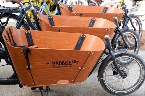 Drei hintereinander aufgereihte Lastenfahrräder der Marke Babboe