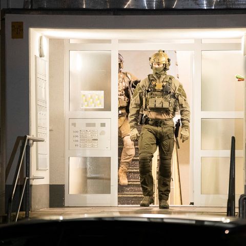 Einsatzkräfte der Polizei verlassen ein Gebäude. Bei einer großangelegten Razzia gegen Schleuser hat die Polizei mehrere Gebäude durchsucht