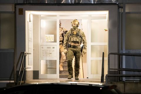 Einsatzkräfte der Polizei verlassen ein Gebäude. Bei einer großangelegten Razzia gegen Schleuser hat die Polizei mehrere Gebäude durchsucht