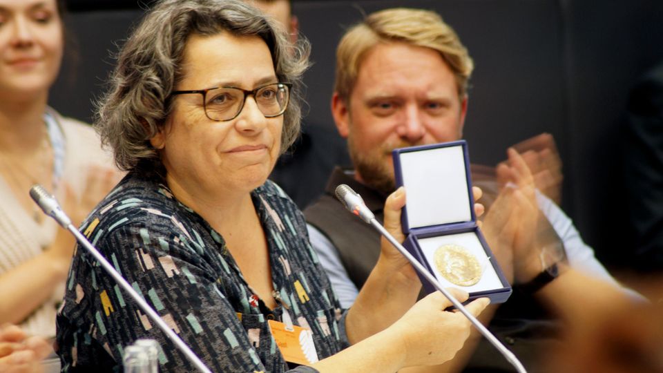 Friedensnobelpreisträgerin: Xanthe Hall wurde 1959 in Schottland geboren. Bereits mit 19 Jahren fing sie an, gegen Atomwaffen zu protestieren. 1985 wanderte sie nach Deutschland aus. Seit 1992 arbeitete sie für den Verband "Internationale Ärzt*innen für die Verhütung des Atomkriegs" (International Physicians for the Prevention of Nuclear War, kurz IPPNW. Dieser rief 2007 die Kampagne ICAN ins Leben (International Campaign to Abolish Nuclear Weapons, internationale Kampagne für die Abschaffung atomarer Waffen). Xanthe Hall begründete 2014 den deutschen Ableger. 2017 gelang unter Mitwirkung dieser Kampagne die Verabschiedung des Atomwaffenverbotsvertrages der UN. Er wurde von 122 Staaten angenommen, allerdings von keiner Atommacht. ICAN erhielt dafür den Friedensnobelpreis. Eine von zwölf Repliken der Medaille besitzt Xanthe Hall. Sie ist verheiratet, hat einen Sohn und lebt in Berlin. Xanthe Hall wurde 1959 in Schottland geboren. Bereits mit 19 Jahren fing sie an, gegen Atomwaffen zu protestieren. 1985 wanderte sie nach Deutschland aus. Seit 1992 arbeitete sie für den Verband "Internationale Ärzt*innen für die Verhütung des Atomkriegs" (International Physicians for the Prevention of Nuclear War, kurz IPPNW. Dieser rief 2007 die Kampagne ICAN ins Leben (International Campaign to Abolish Nuclear Weapons, internationale Kampagne für die Abschaffung atomarer Waffen). Xanthe Hall begründete 2014 den deutschen Ableger. 2017 gelang unter Mitwirkung dieser Kampagne die Verabschiedung des Atomwaffenverbotsvertrages der UN. Er wurde von 122 Staaten angenommen, allerdings von keiner Atommacht. ICAN erhielt dafür den Friedensnobelpreis. Eine von zwölf Repliken der Medaille besitzt Xanthe Hall. Sie ist verheiratet, hat einen Sohn und lebt in Berlin.