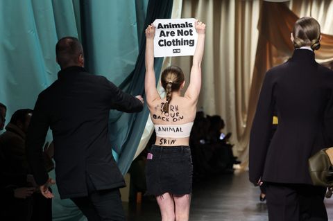 Eine Demonstrantin läuft über den Laufsteg der Fendi-Modenschau während der Mailänder Fashion Week