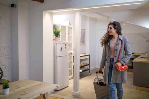 Eine Frau geht mit ihrem Rollkoffer durch eine Ferienwohnung