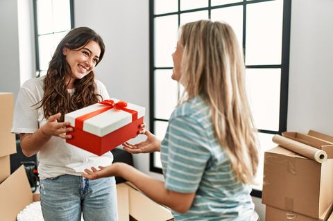 Frau überrascht ihre Freundin mit Geschenk im neuen Zuhause