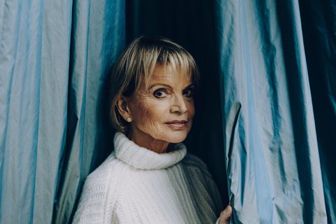 Hier schaut Uschi Glas zwischen einem Vorhang hindurch