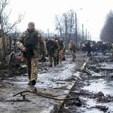 Ukrainische Soldaten inspizieren die Trümmer einer zerstörten russischen Panzerkolonne auf einer Straße in Butscha