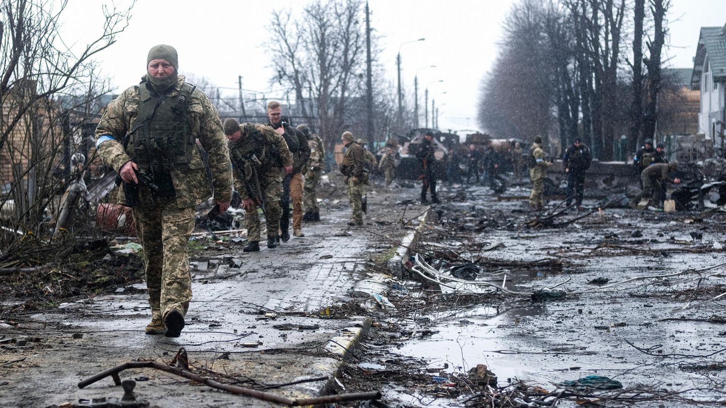 Ukrainische Soldaten inspizieren die Trümmer einer zerstörten russischen Panzerkolonne auf einer Straße in Butscha
