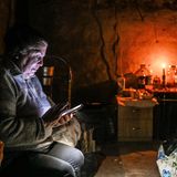 Eine alte Dame sitzt in einem mit Kerzen erleuchteten Raum