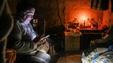 Eine alte Dame sitzt in einem mit Kerzen erleuchteten Raum