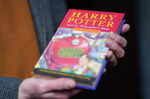Ein Auktionator hält eine Erstausgabe des ersten Harry Potter Bands in der Hand