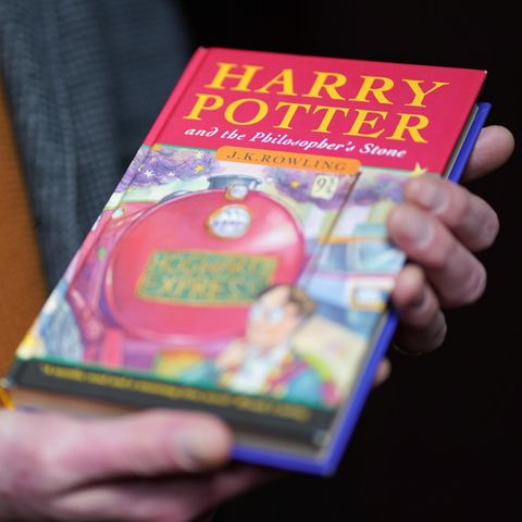 Ein Auktionator hält eine Erstausgabe des ersten Harry Potter Bands in der Hand