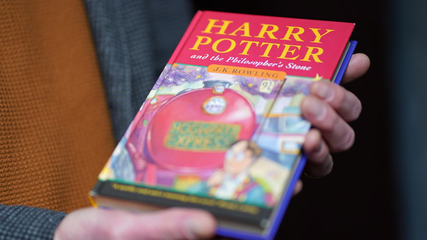 Ein Auktionator hält eine Erstausgabe des ersten Harry Potter Bands in der Hand