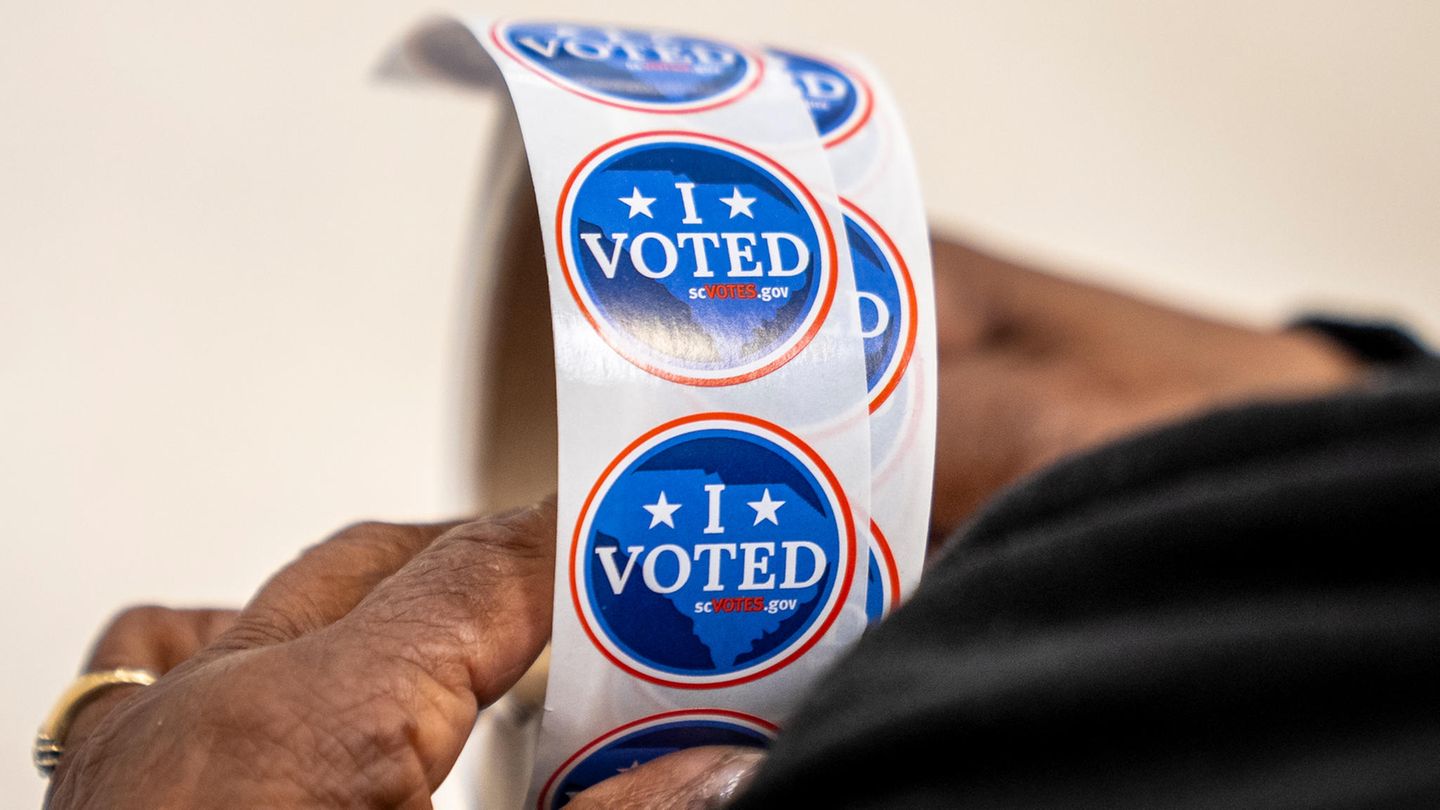 Ein Wahlhelfer hält eine Rolle mit "I voted"-Aufklebern