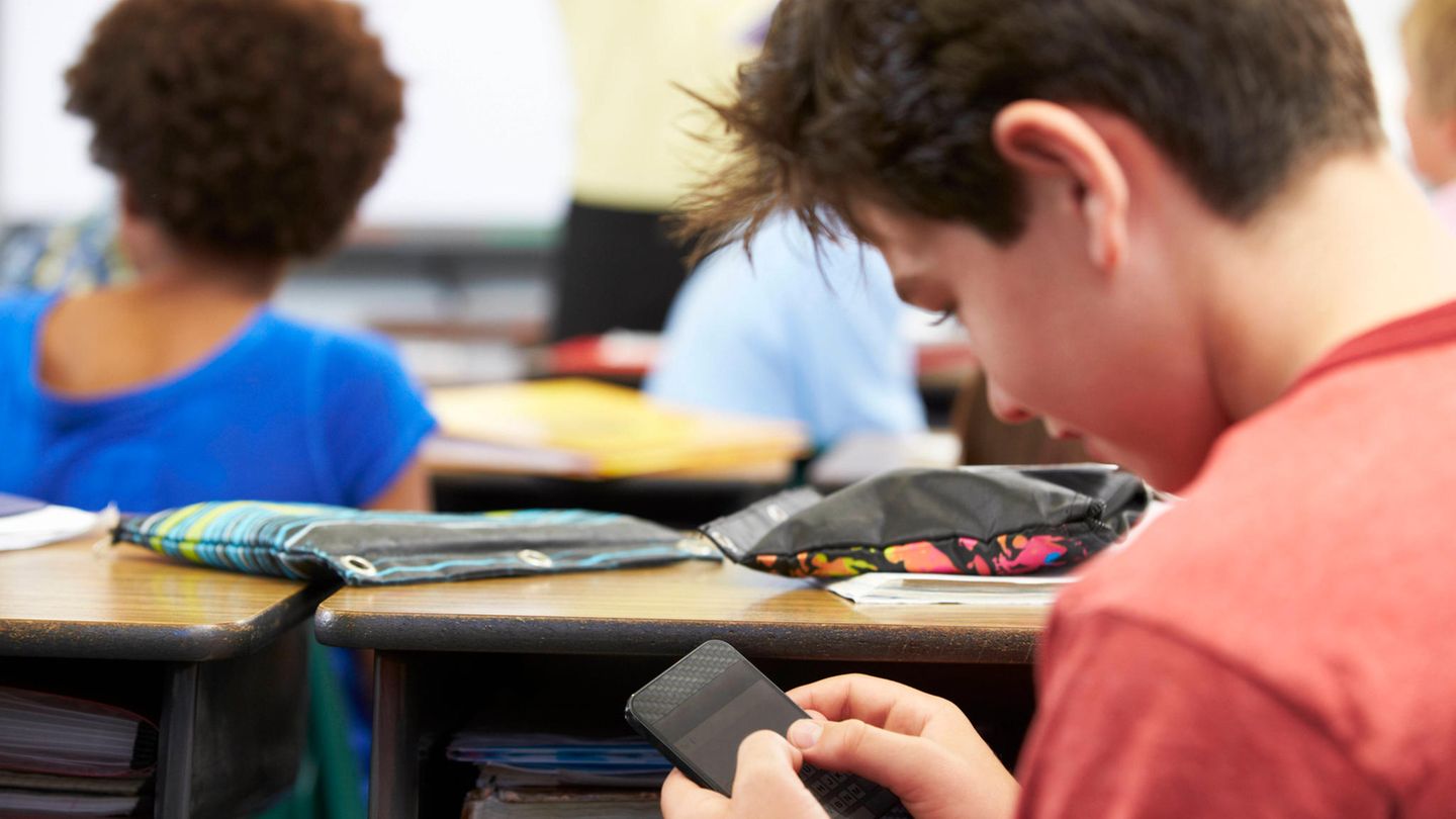 Handyverbot an Schulen: Junge schaut während des Unterrichts heimlich auf sein Handy