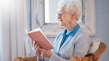 Foto einer Seniorin im Sessel, lesend