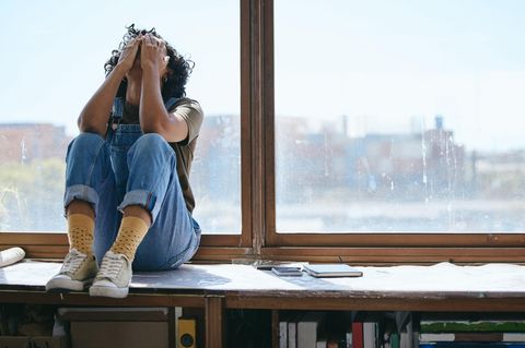 Frau sitzt neben Notizbüchern und hat Prüfungsangst