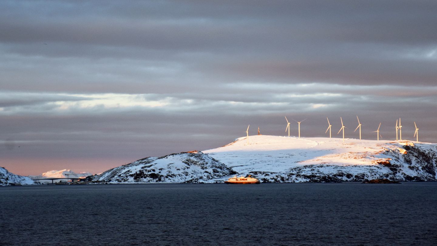 Von Süden kommend steuert ein Schiff von Hurtigruten den Hafen von Havøysund an. Der kleine Ort bezieht seine elektrische Energie aus dem nördlichsten Windpark Europas.