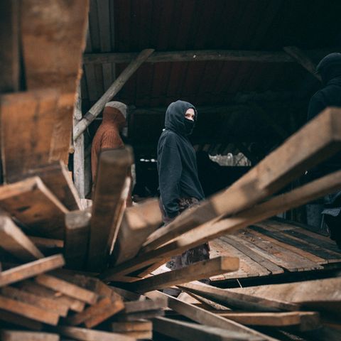 Eine vermummte Person nahe des Tesla-Werks, im Vordergrund Holzbretter