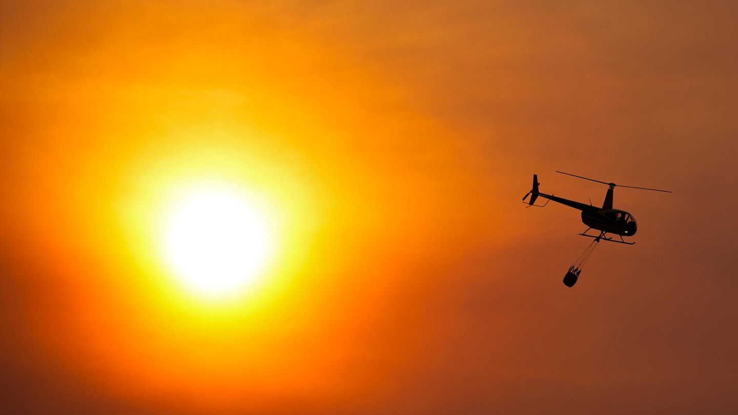 Wäre es nicht so dramatisch, könnte man sich an dem Licht erfreuen. Tatsächlich fliegt hier aber ein Hubschrauber mit einem Wassersack zu einem Löscheinsatz