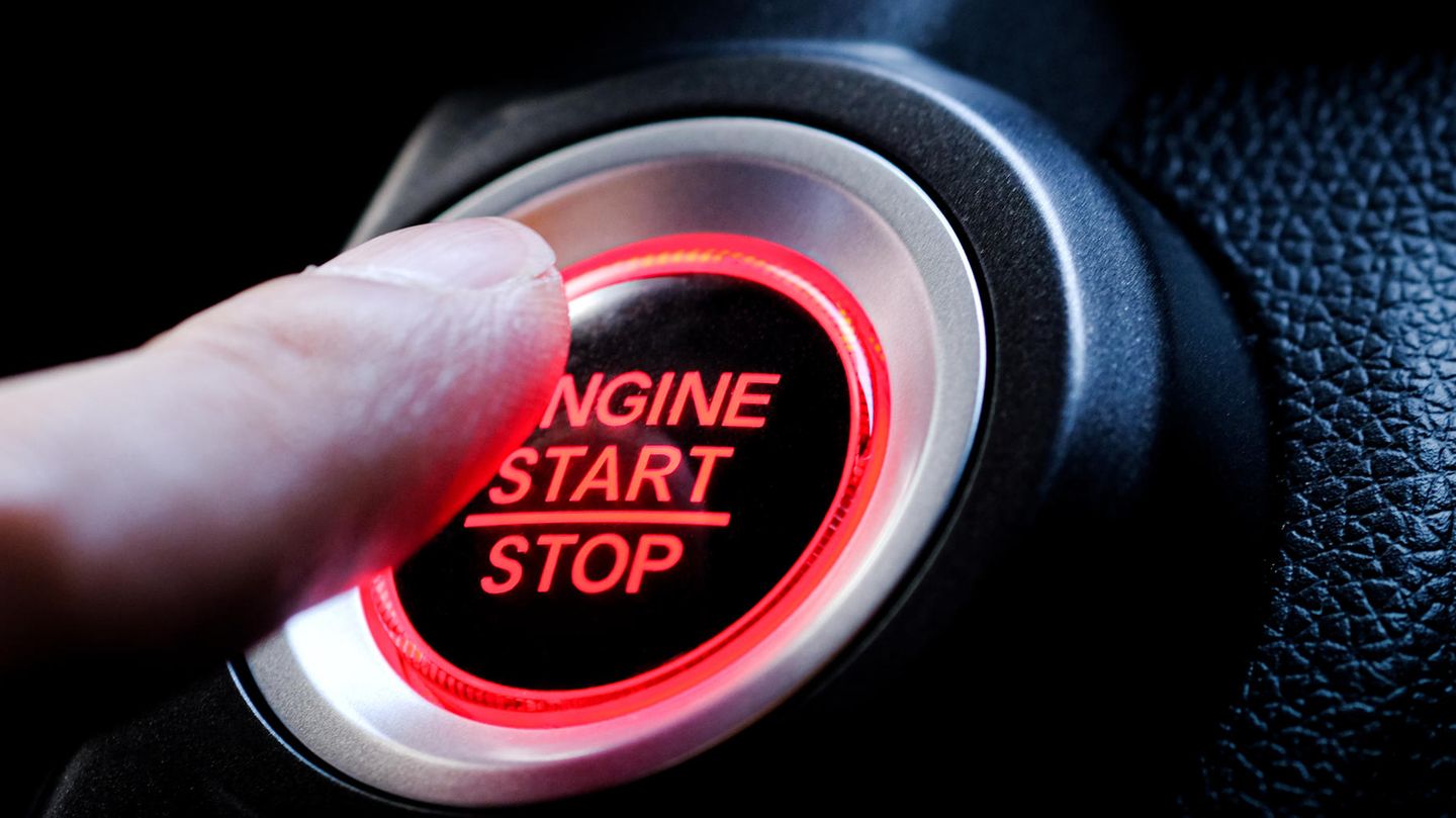 Ein Finger drückt auf den Startknopf eines Autos