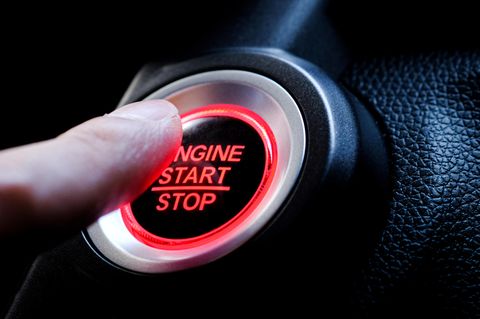 Ein Finger drückt auf den Startknopf eines Autos
