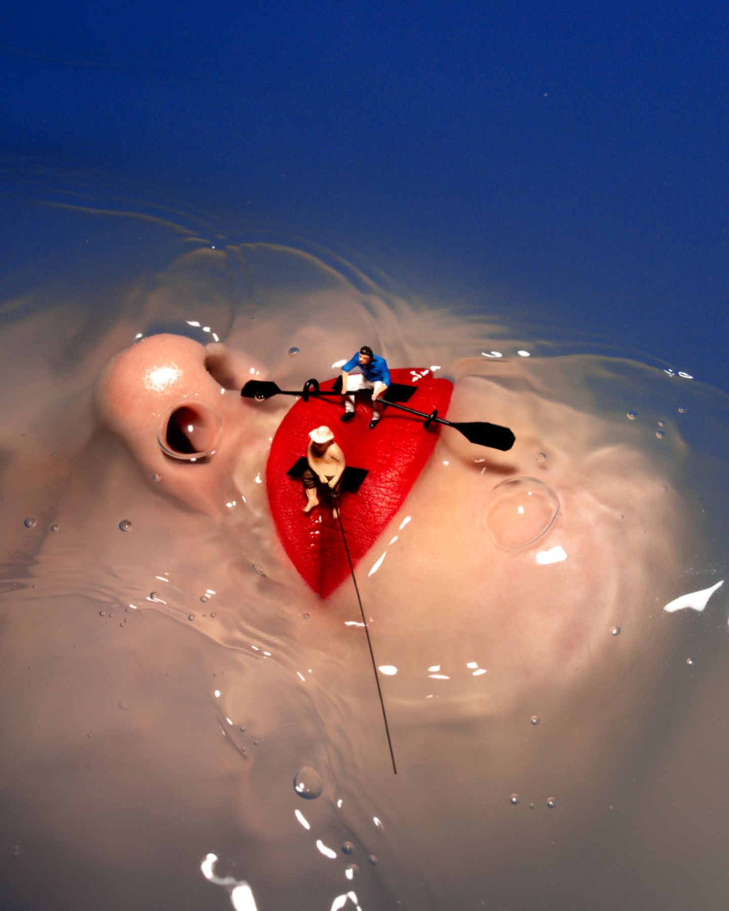 Frauengesicht unter Wasser, nur Nase und roter Mund ragen heraus. Miniaturfiguren sitzen wie Ruderer und Angler auf den Lippen.