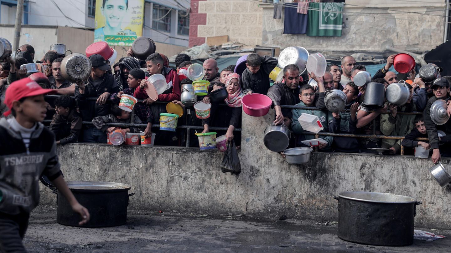 Katastrophe in Gaza: Ausgezehrt und müde sind ihre Gesichter: Palästinenser warten an einer Essensausgabe in einem Flüchtlingslager im südlichen Gazastreifen auf Lebensmittel Ausgezehrt und müde sind ihre Gesichter: Palästinenser warten an einer Essensausgabe in einem Flüchtlingslager im südlichen Gazastreifen auf Lebensmittel