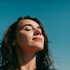 Symbolbild People Pleaser, Mut zum Nein sagen: Eine Frau lässt dich die Sonne ins Gesicht scheinen.