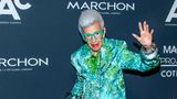 Iris Apfel winkend und im Blumenanzug