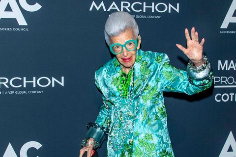 Iris Apfel winkend und im Blumenanzug