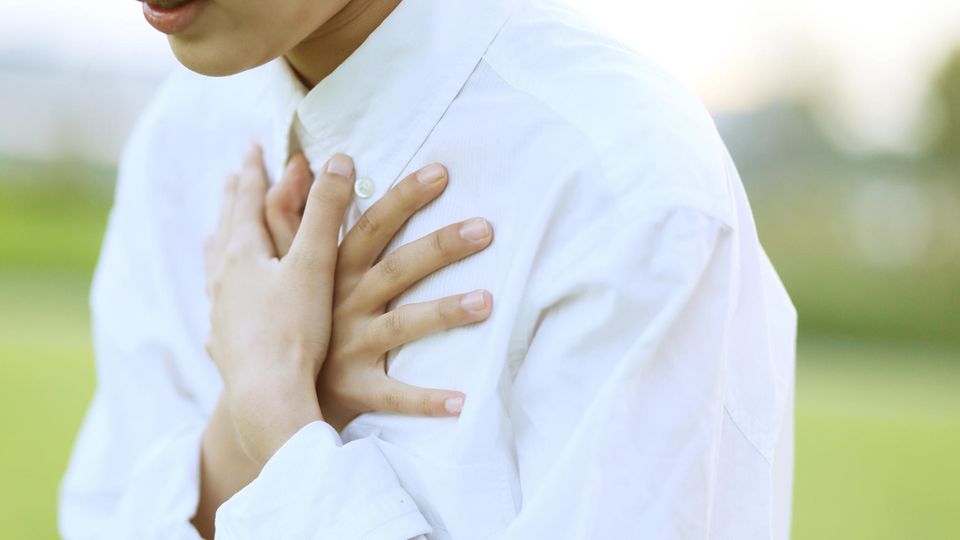 Eine Frau hält sich beide Hände schützend vor ihr Herz