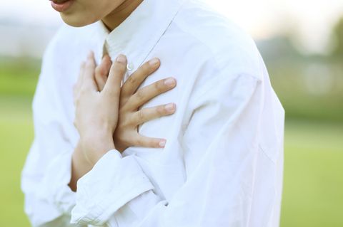 Eine Frau hält sich beide Hände schützend vor ihr Herz