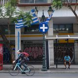 Ein Mann fährt auf einem Fahrrad über eine Straße in Athen