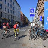 Ein Mann und eine Frau fahren bei Sonnenschein durch Kopenhagen