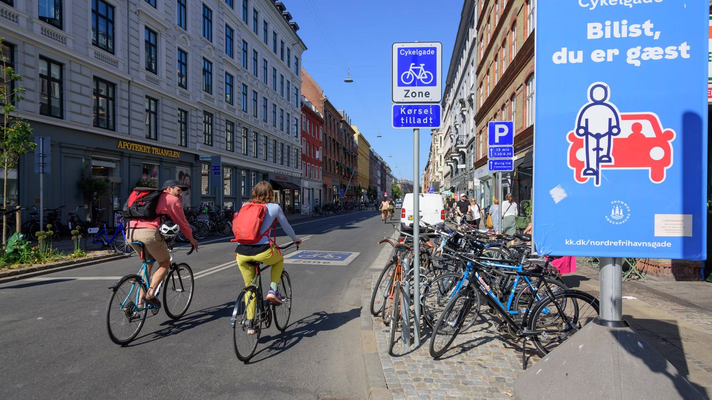 Ein Mann und eine Frau fahren bei Sonnenschein durch Kopenhagen