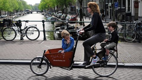 Eine Frau ist mit zwei Kindern per Fahrrad unterwegs