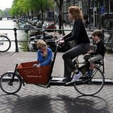 Eine Frau ist mit zwei Kindern per Fahrrad unterwegs