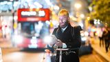 Ein Mann in London steht mit einem Fahrrad auf einer abendlichen Straße