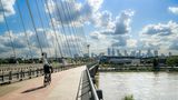 Ein Radfahrer fährt bei Sonnenschein über eine Brücke in Warschau